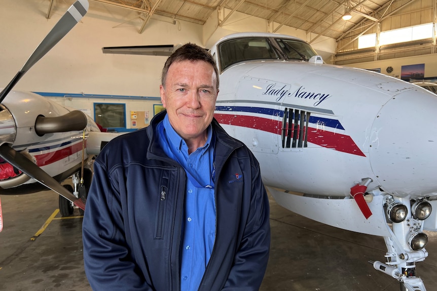 Man stands in front of Royal Flying Doctor Service plane