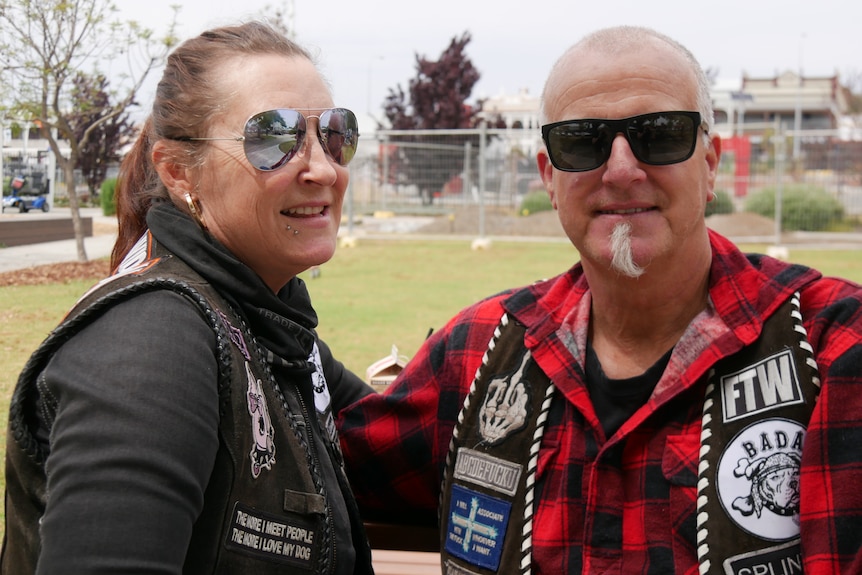 A woman wearing sunglasses smiles next to a man with sunglasses and a goatie, he's also smiling.