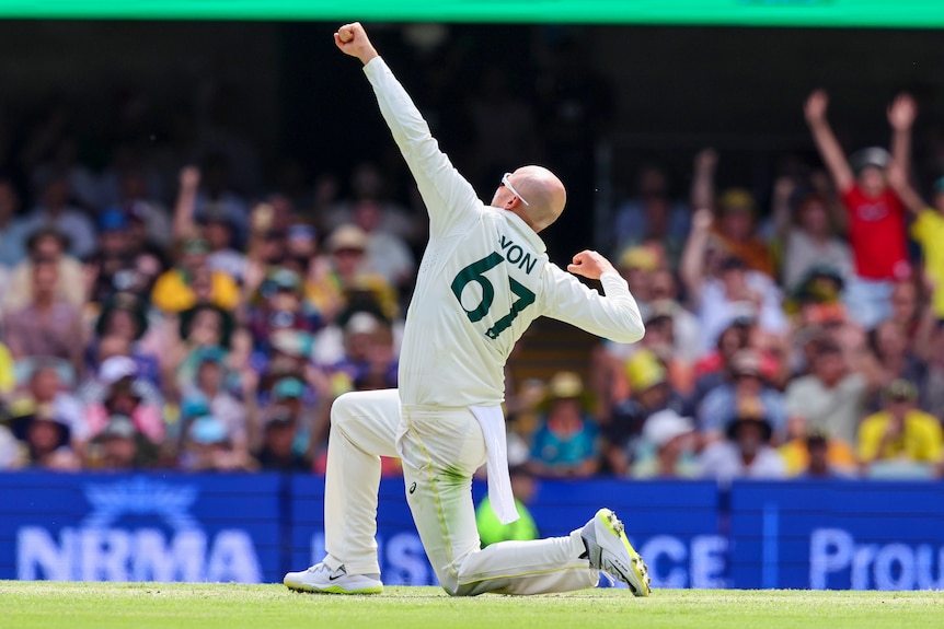 El jugador de bolos australiano Nathan Lyon, sobre una rodilla, aprieta el puño y golpea el aire durante una prueba contra Sudáfrica.