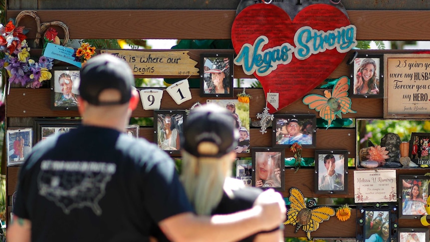 People visit a memorial wall with pictures and notes for victims of a mass shooting in Las Vegas.