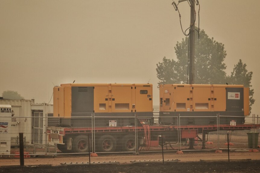 Power generators sit in front of a smoky sky.