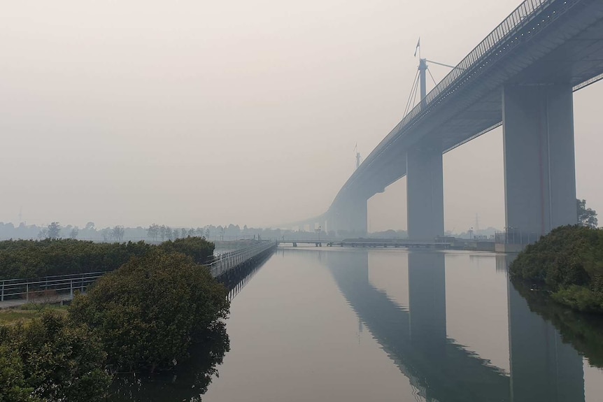 The West Gate Bridge is half-obscured by thick smoke pollution.