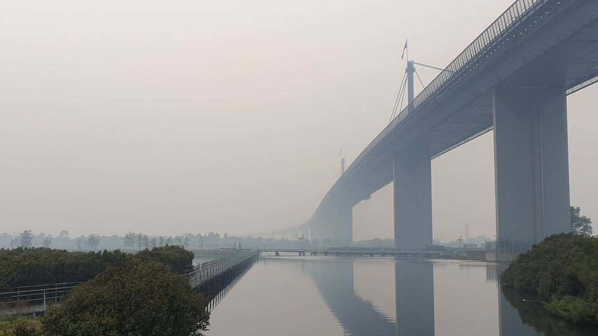 The West Gate Bridge is half-obscured by thick smoke pollution.