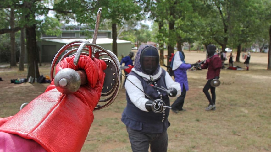 People taking part in fencing in a park.