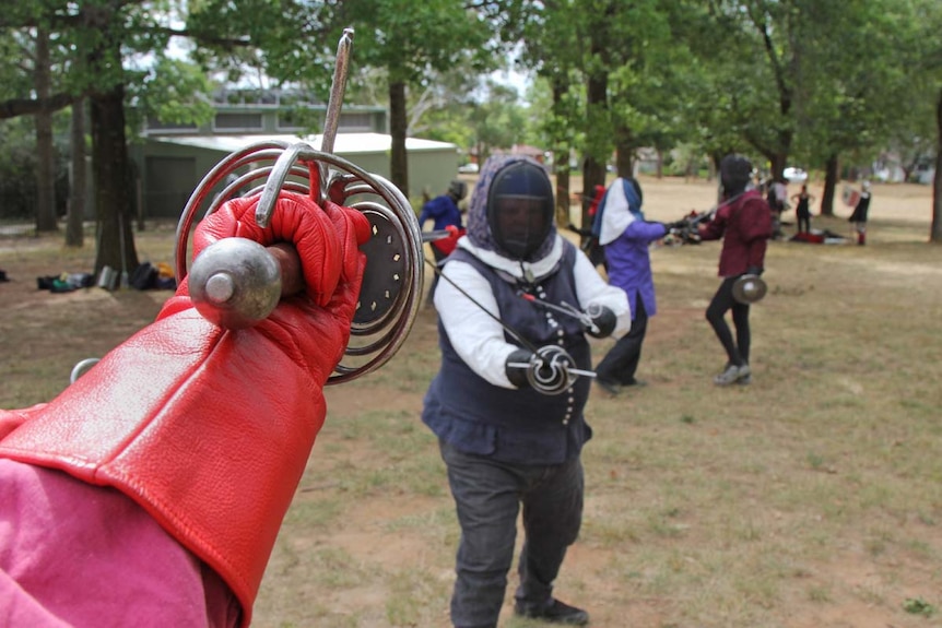 People taking part in fencing in a park.