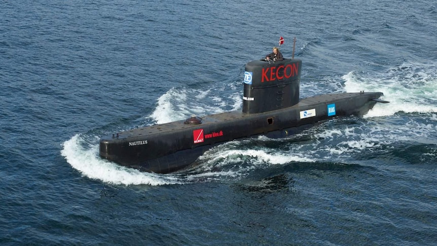 A submarine on the surface with  man standing in the conning tower