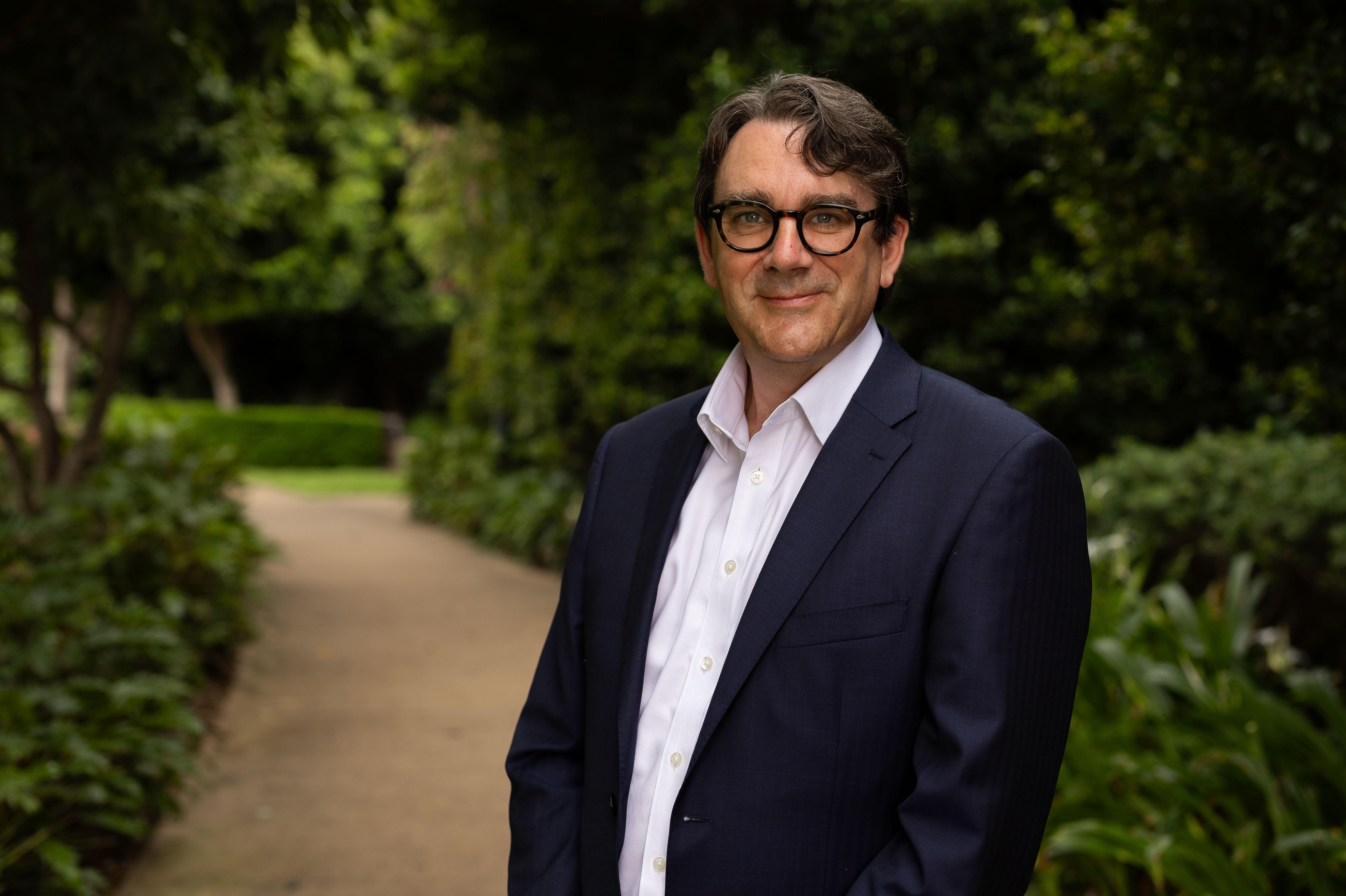 Man in glasses and suit standing among greenery
