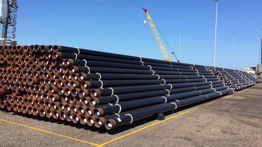 A stack of pipes with cranes in the background