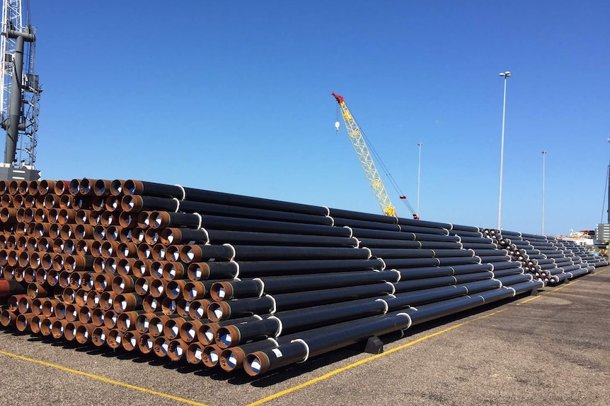 A stack of pipes with cranes in the background