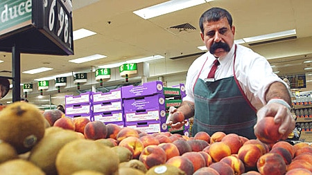 Woolworths staff add fruit to a display