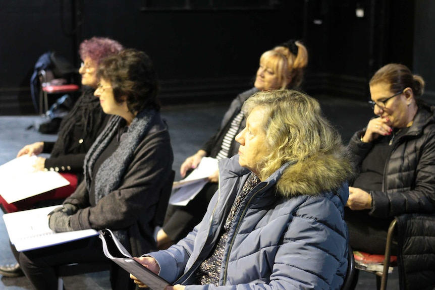 A group of older women sitting on chairs with books of music notation