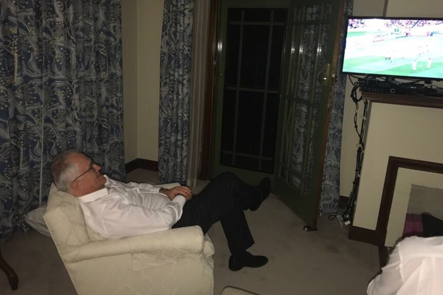 Malcolm Turnbull lying back in an arm chair watching the Socceroos beat Honduras on television