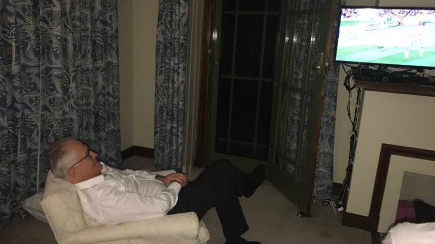 Malcolm Turnbull lying back in an arm chair watching the Socceroos beat Honduras on television