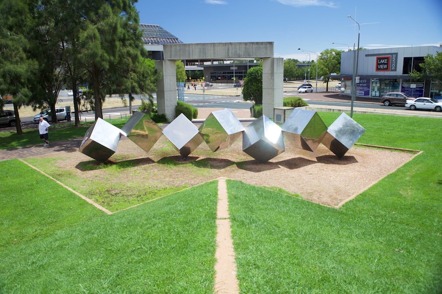 A passer by looks at the Tumbling Cubes sculpture  in Belconnen.