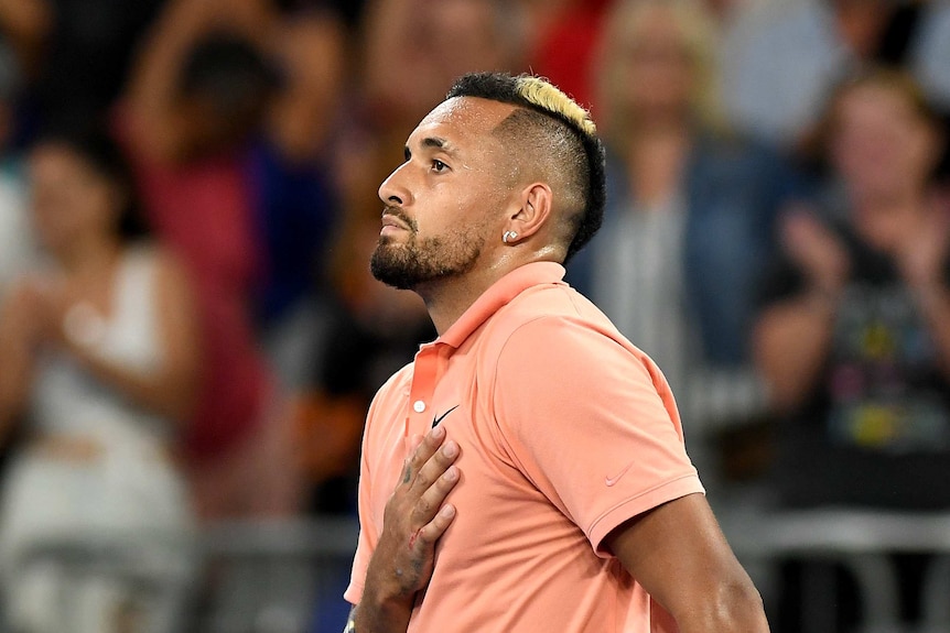 A male tennis player celebrates winning a match at the Australian Open by placing his hand on his heart.