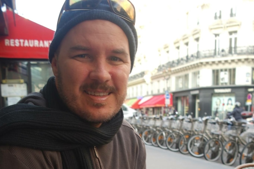 Matt smiling, creme brulee and espresso sitting on the table next to him, bikes in background.