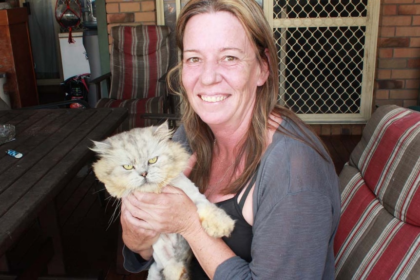 Woman in her mid forties holding cat with a big fluffy head.