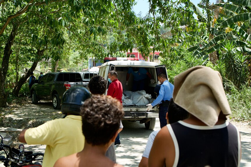 People watch as a body is loaded into an ambulance.
