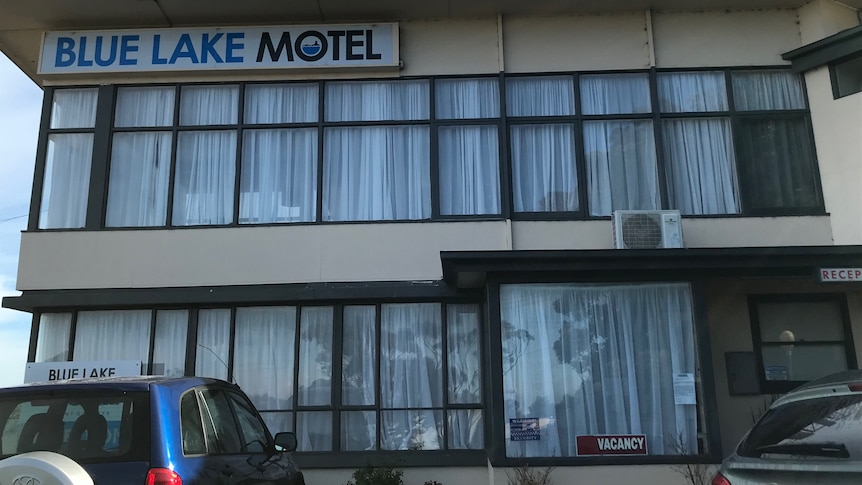 The front of a motel with windows and cars parked at the front