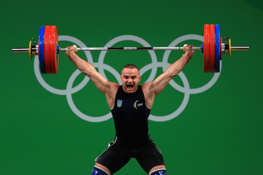 Weightlifter Oleksandr Pielieshenko with a bar over his head, at the Olympic Games
