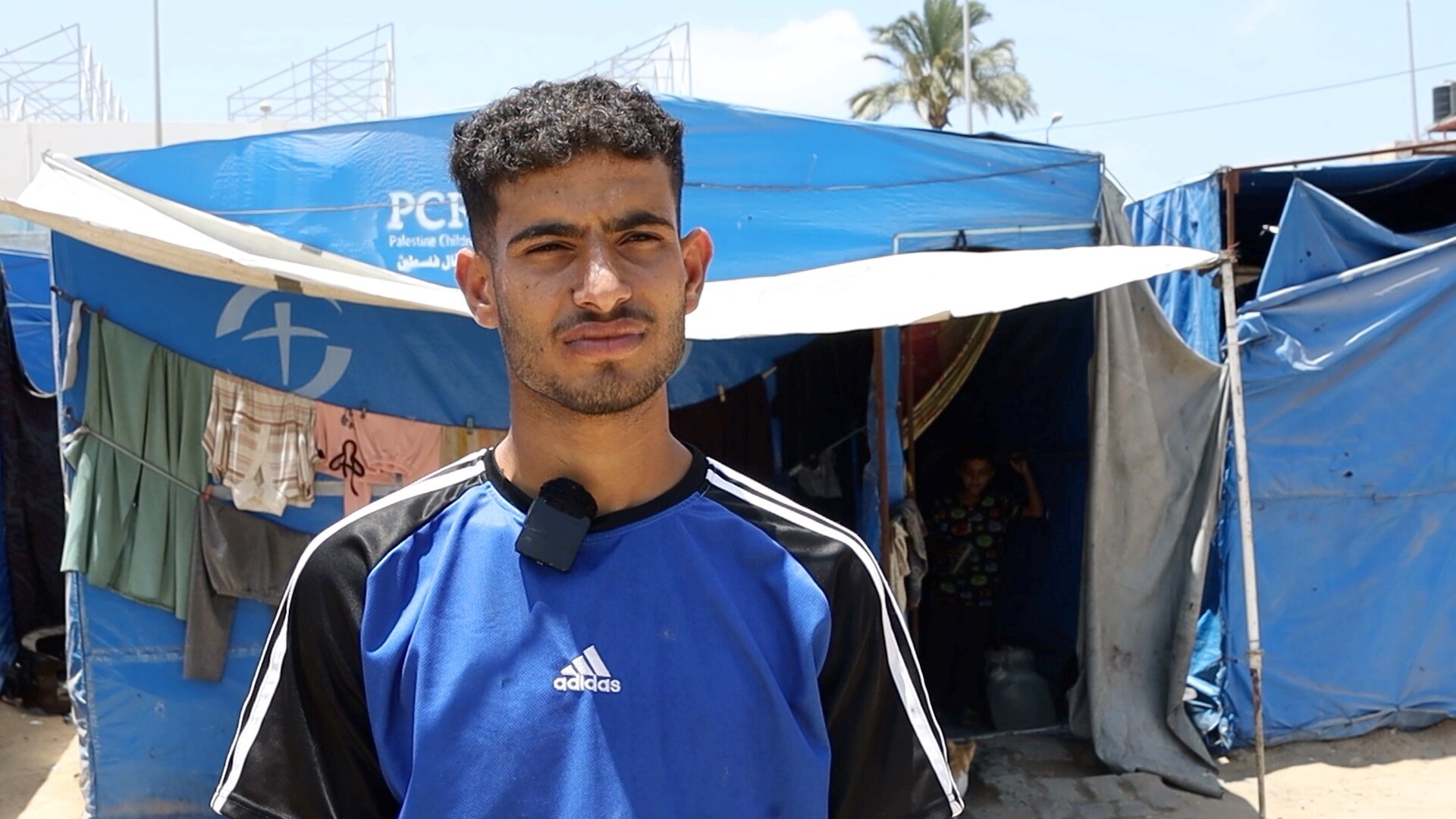 A man in a football jersey in front of a tent. 