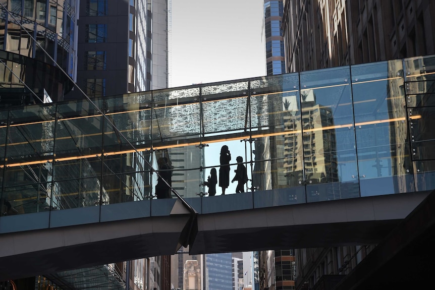 The silhouette of a woman on a mobile phone on a pedestrian walkway between buildings in the Sydney CBD.