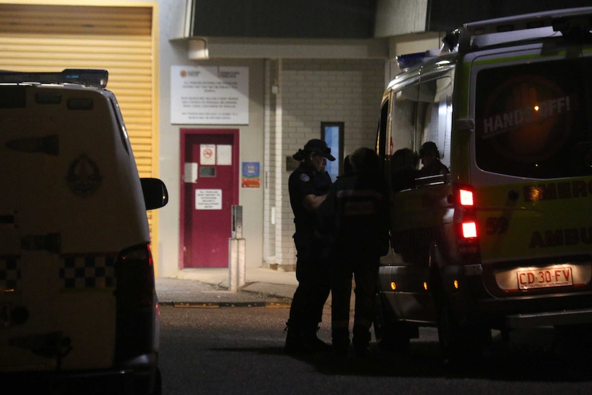 Police consult beside a van in the dark.