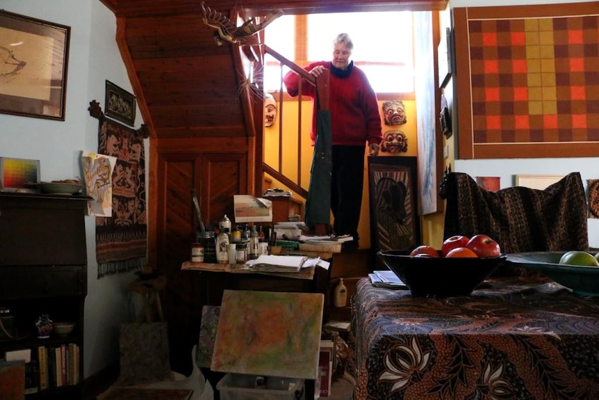 Barbara McKay coming down the stairs in her art-filled cottage.