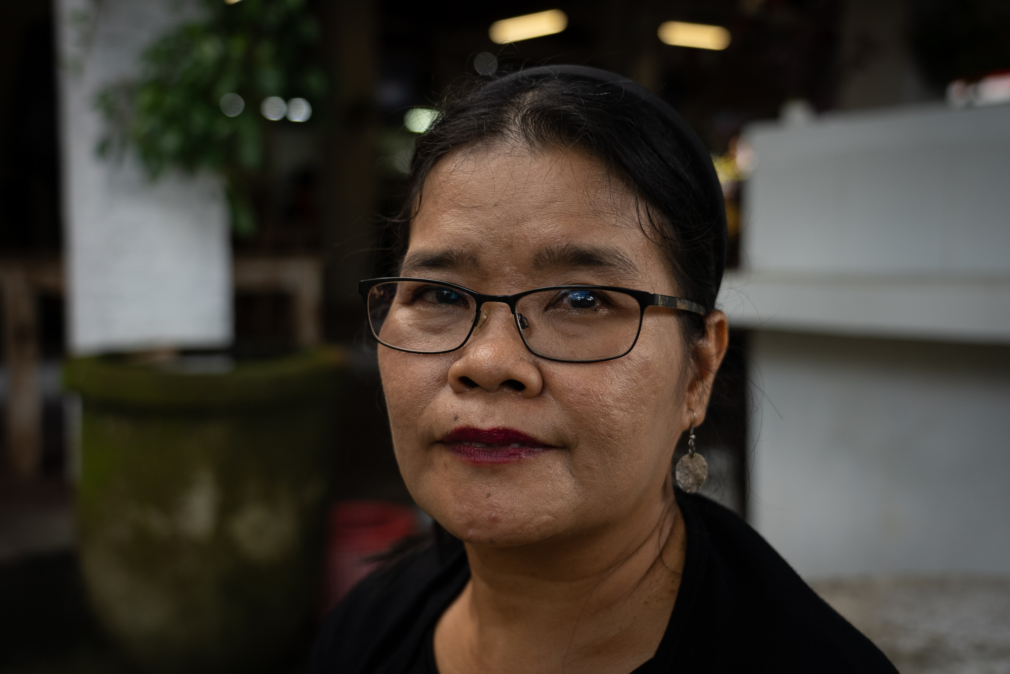 A close up of a woman wearing glasses and red lipstick with her hair pulled back in a ponytail.