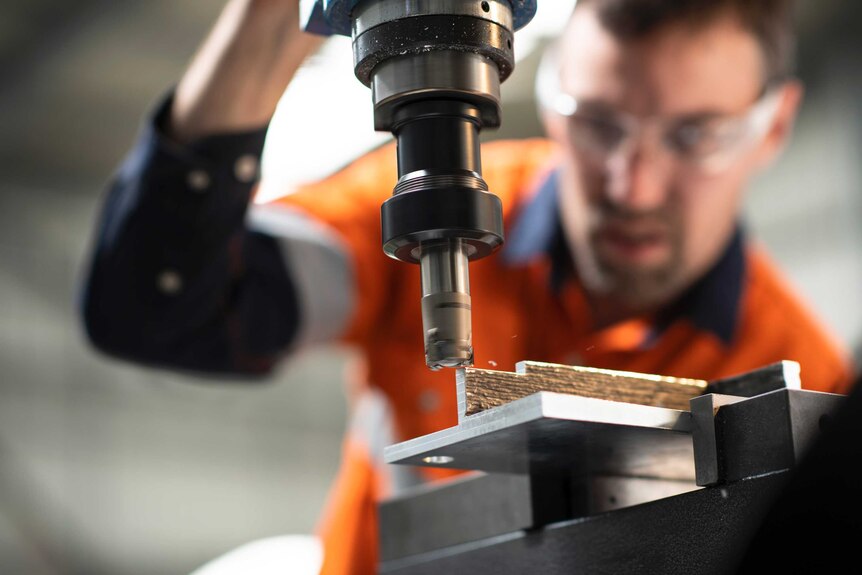 A worker uses a tool to shape metal at AML3D's factory in Adelaide