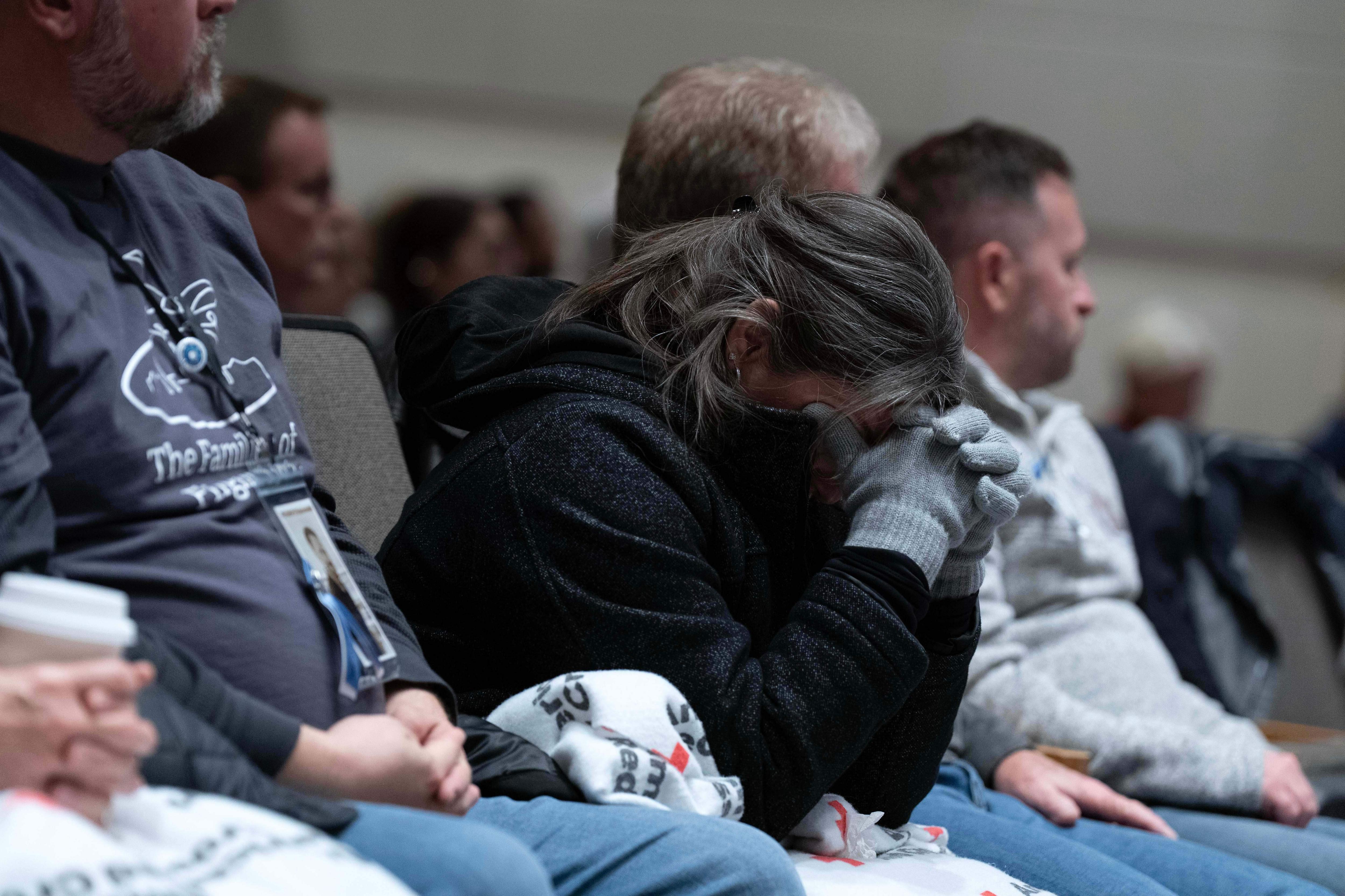 Una foto de una mujer llorando en sus manos mientras escucha la audiencia.