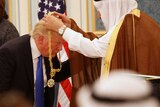Donald Trump bends down as Saudi King Salman hangs a gold medallion around his neck