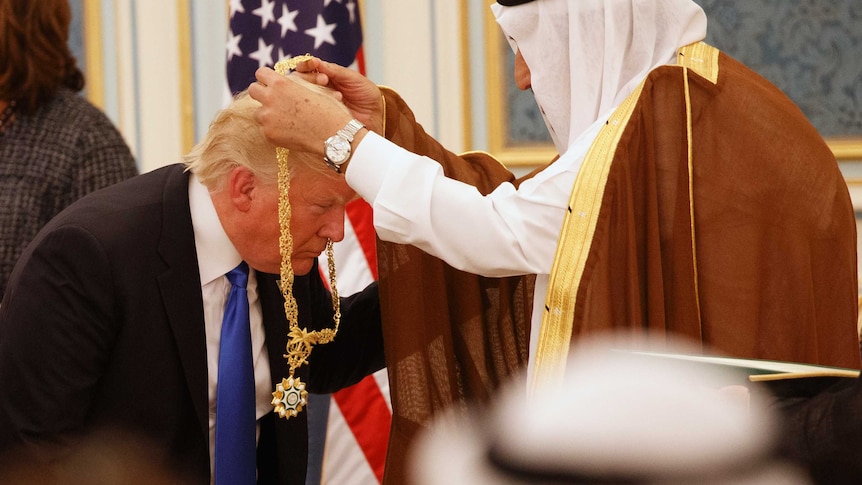 Donald Trump bends down as Saudi King Salman hangs a gold medallion around his neck