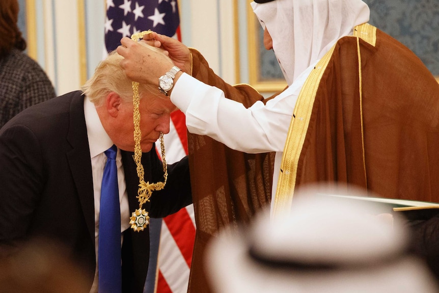 Donald Trump bends down as Saudi King Salman hangs a gold medallion around his neck