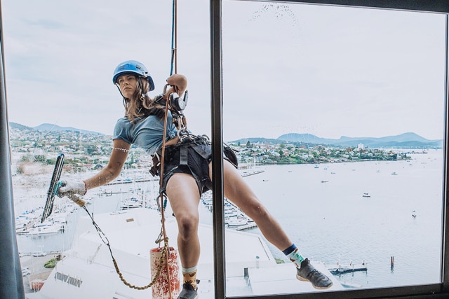 Skye-Blue Henderson hanging off ropes cleaning windoww