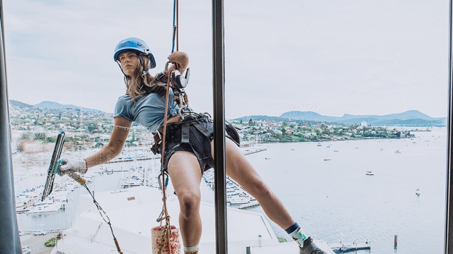 Skye-Blue Henderson hanging off ropes cleaning windoww