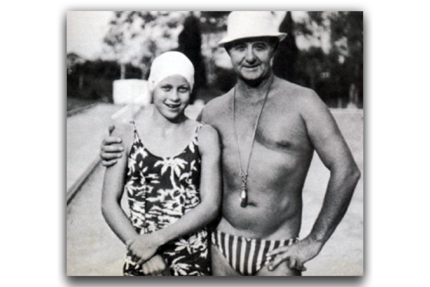 a black and white image of a young female swimmer in a swim cap with a man wearing speedos and bucket hat