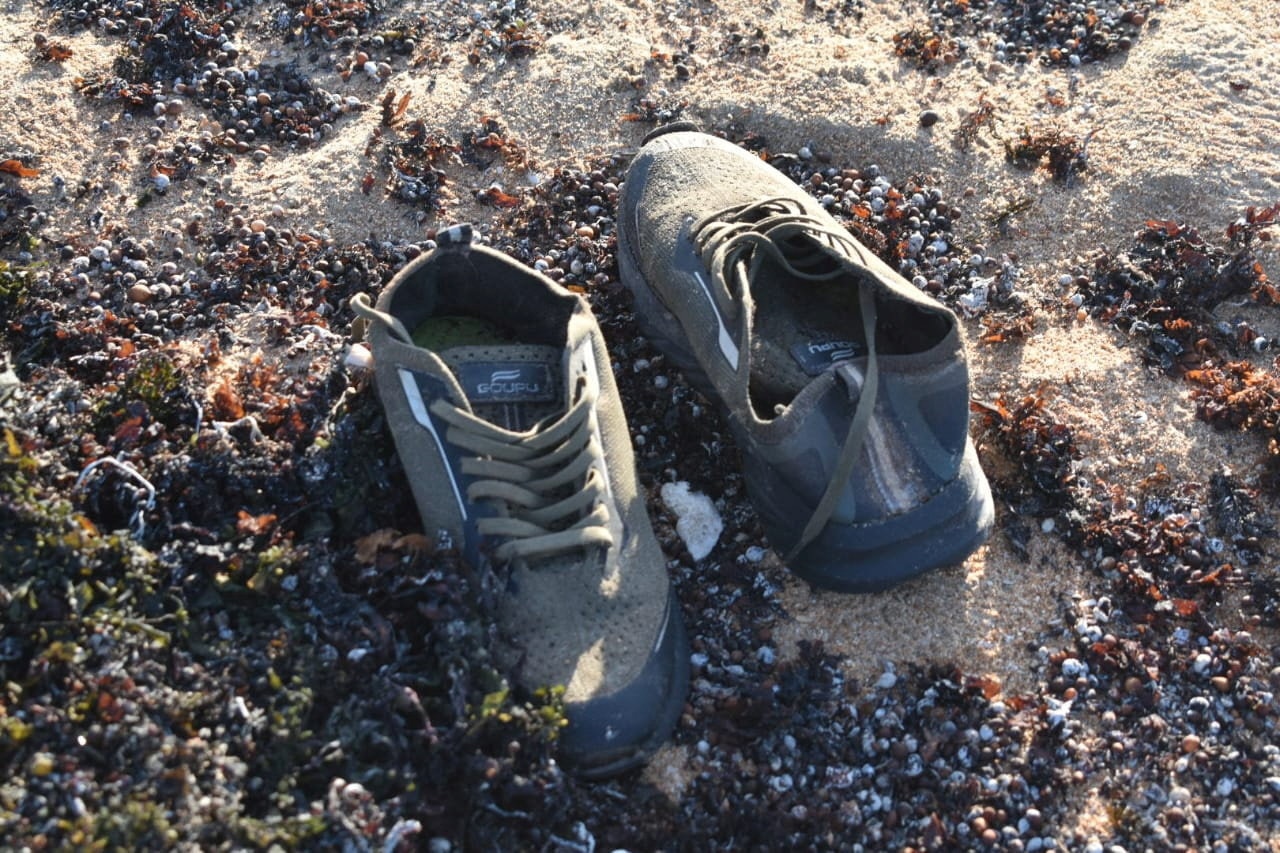 A pair of grey shoes on the beach.