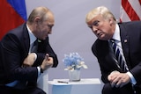Donald Trump and Vladimir Putin lean over the arms of their chairs during a meeting in the G20.