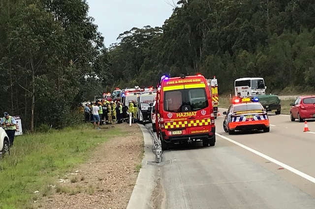 A red and yellow fire and rescue van and other emergency services personnel beside the highway.