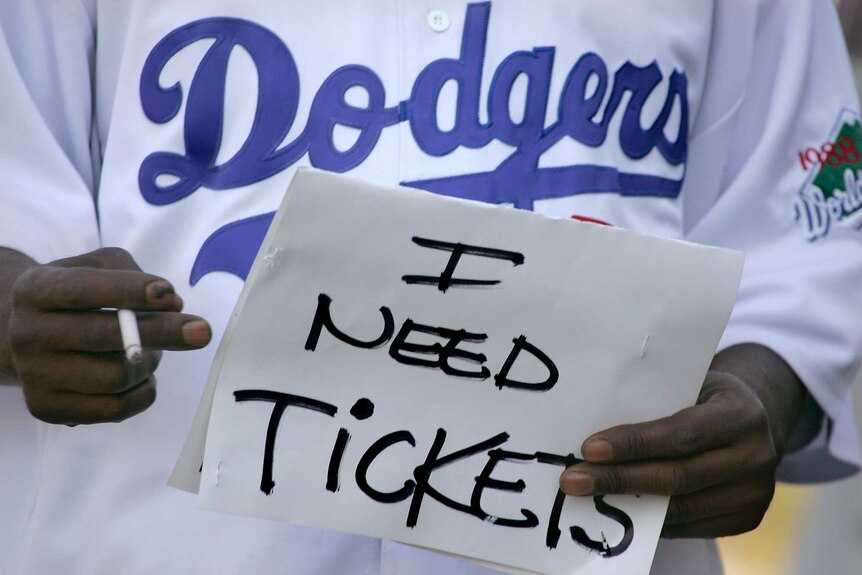A person holding a sign saying 'I need tickets'
