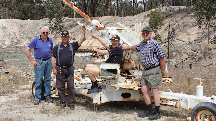 Members of the Narrogin Men's Shed stand next to a rusty 1945 Bofors anti-aircraft gun from WWII.