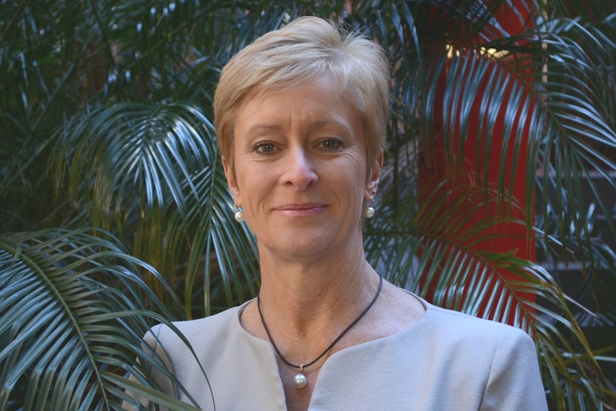 Vanessa Guthrie stands in front of some thick fern-based foliage