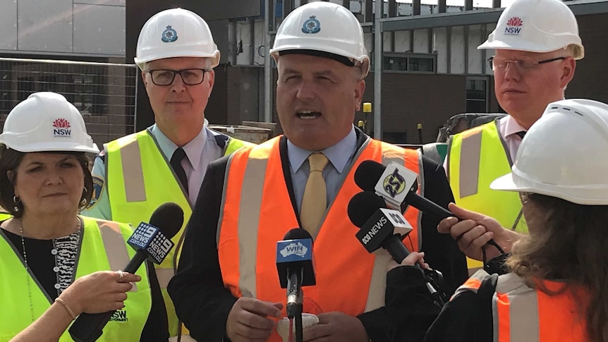 Corrective services minister David Elliot speaks to the media wearing a hard hat at a press conference in South Nowra.