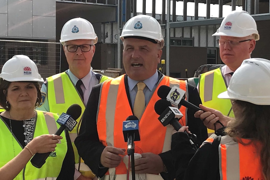 Corrective services minister David Elliot speaks to the media wearing a hard hat at a press conference in South Nowra.