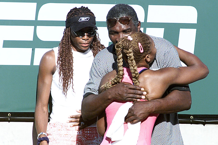 Serena Williams hugs Richard Williams with Venus Williams watching on