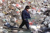 Boy crosses stream in rubbish tip, China