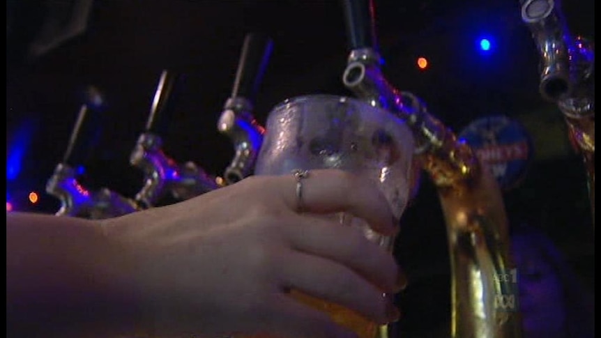 A hand pours a glass of beer from a tap in a pub