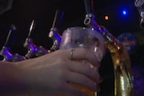 A hand pours a glass of beer from a tap in a pub