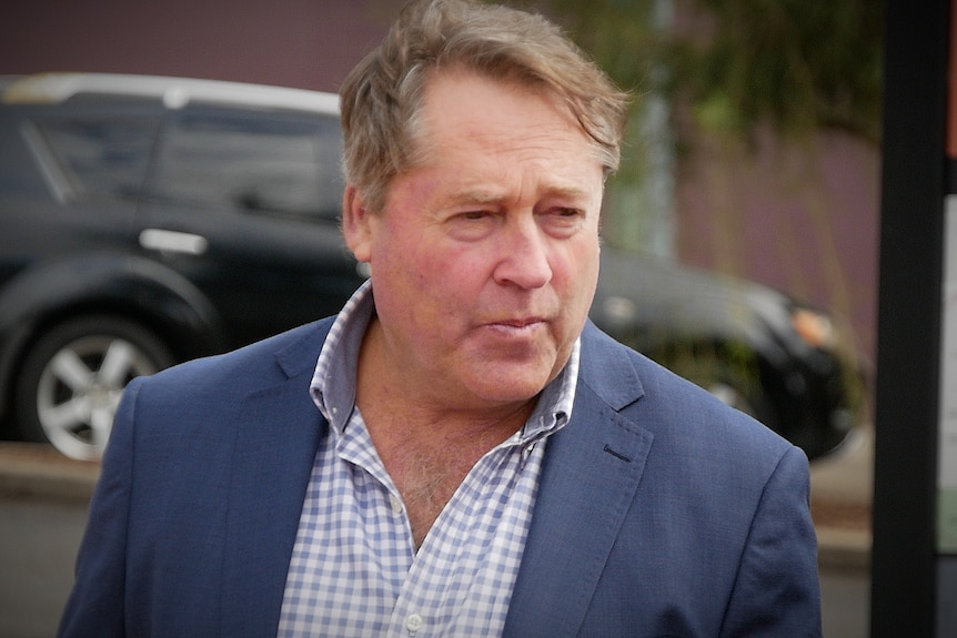 A man in a blue suit and checked shirt walking